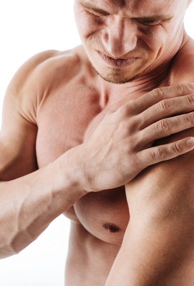 Cropped image of sad young sportsman standing isolated over white background and have a painful feelings in body.